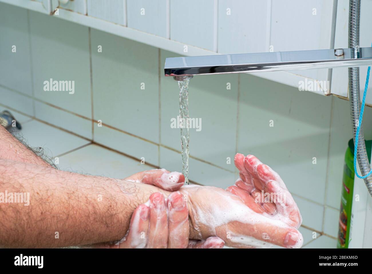 Ein Mann wäscht sich im Bad unter fließendem Wasser die Hände mit Seife Stockfoto