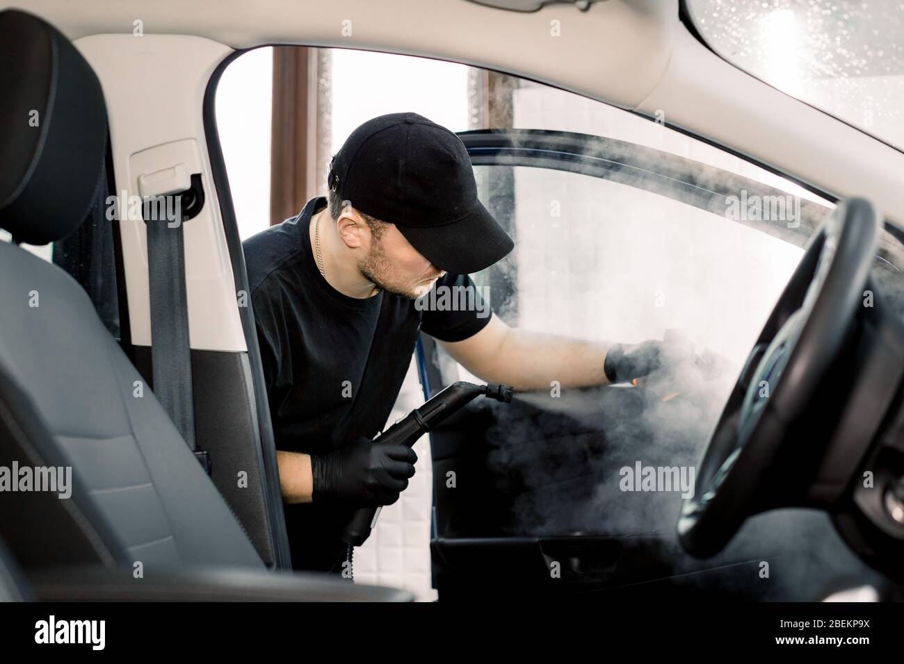 Auto-Reinigungsservice und Detaillierung Konzept. Schöner kaukasischer Mann  in schwarz einheitliche Reinigung Innenraum des Autos mit heißem  Dampfreiniger. Selektiv Stockfotografie - Alamy