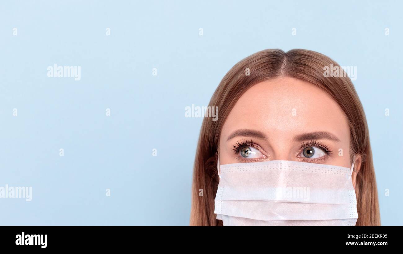 Nahaufnahme der Frau mit Schutzmaske, Blick beiseite auf Kopierraum, isoliert auf blauem Hintergrund. Grippe, Allergie, Schutz gegen Viren, Coronavir Stockfoto