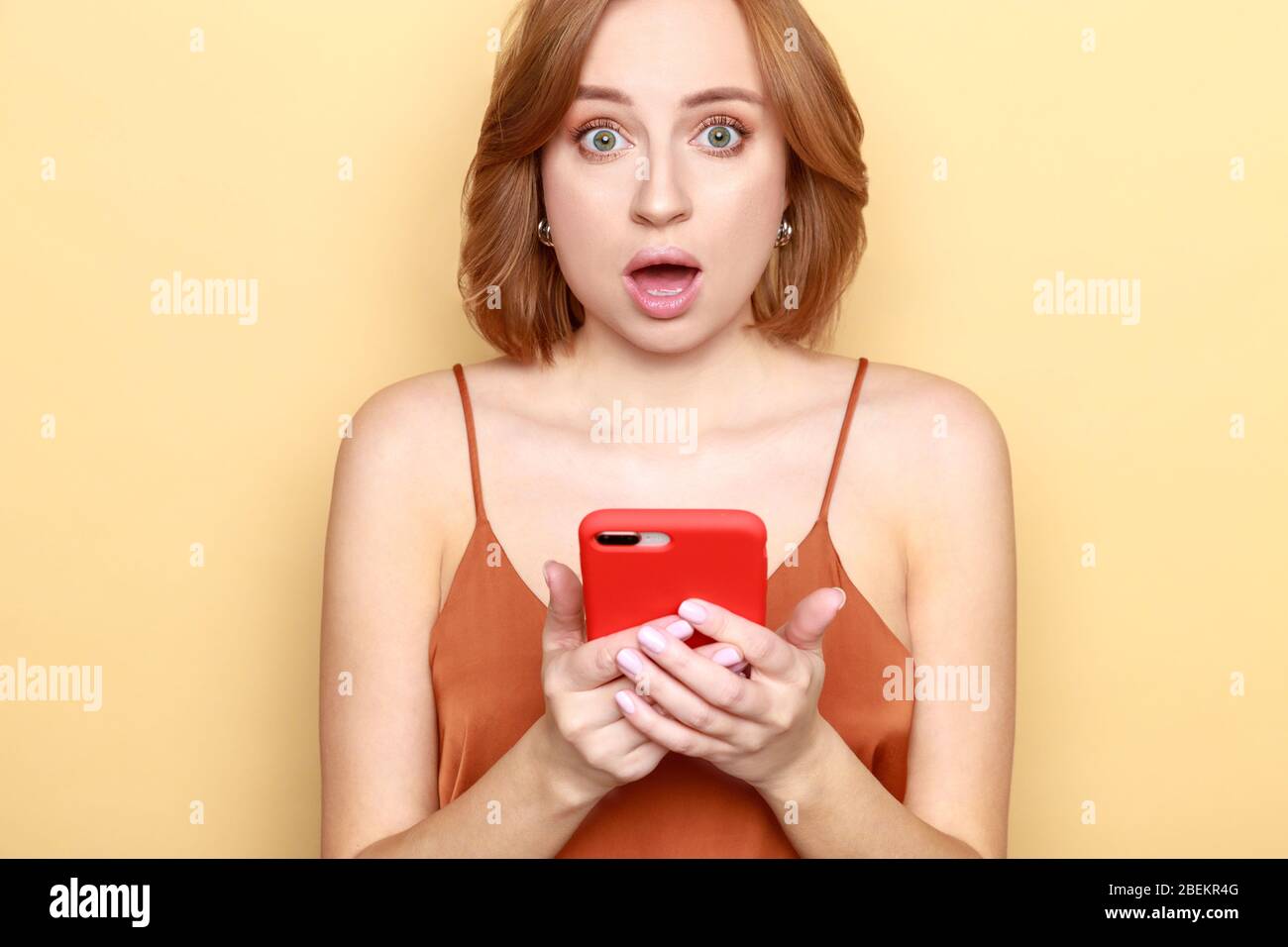 Porträt von schockierten oder ängstlich junge Frau Smartphone halten, Blick auf die Kamera mit offenem Mund, hat Gesichtsausdruck überrascht, schockiert durch Preise, Stockfoto