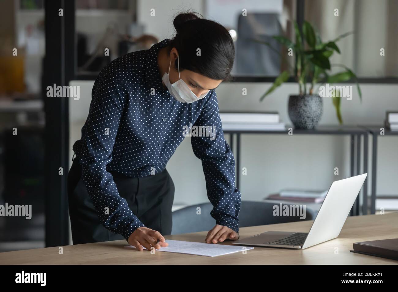 Weibliche Angestellte in Gesichtsmaske Arbeit im Büro Stockfoto