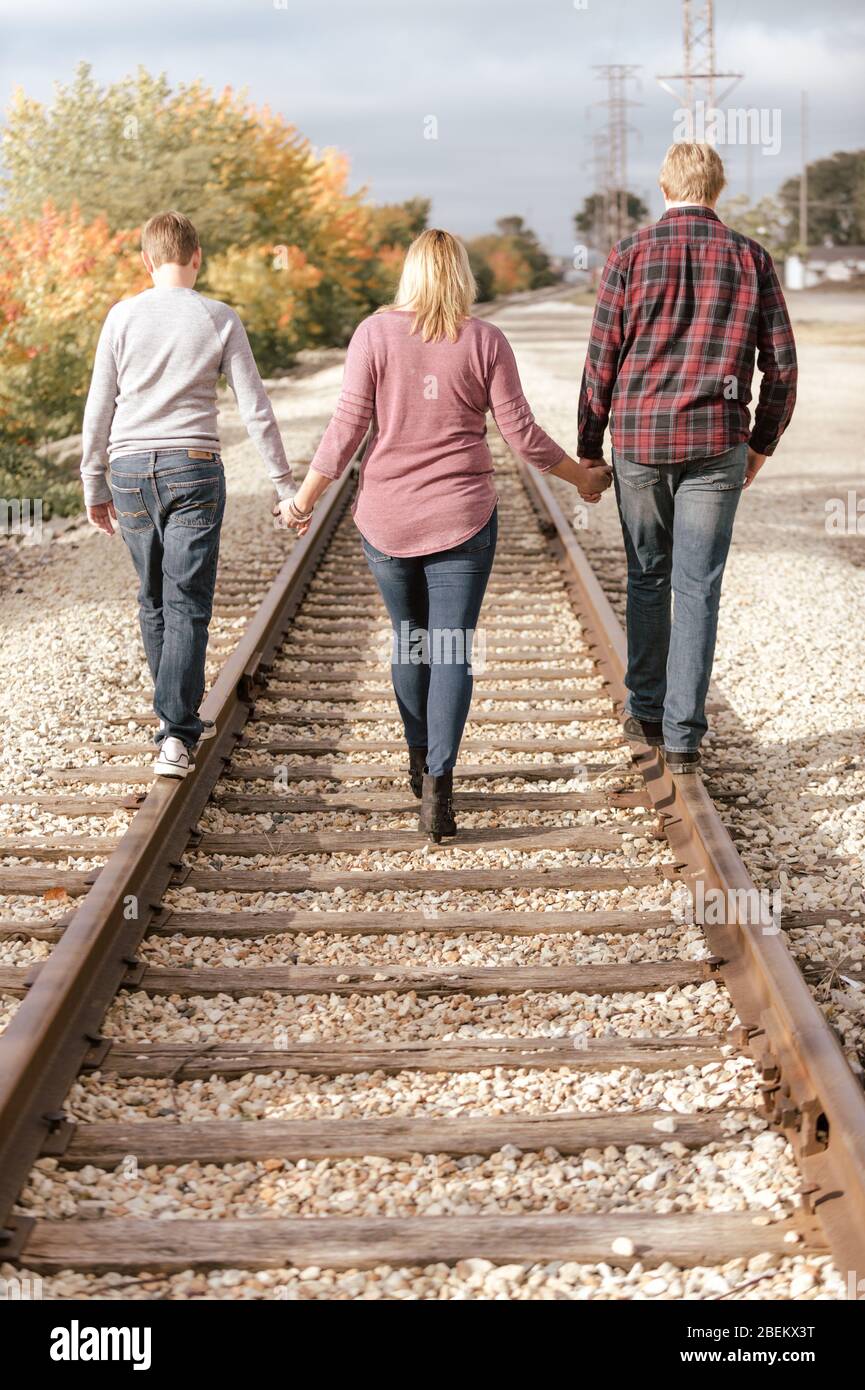 Mutter und ihre Söhne gehen Hand in Hand auf Eisenbahnschienen Stockfoto