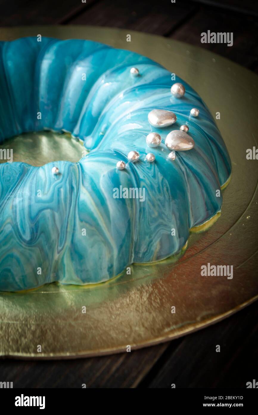 Mousse Kuchen im maritimen Stil mit blauen Spiegel Glasur und Silber Dekoration bedeckt. Stockfoto