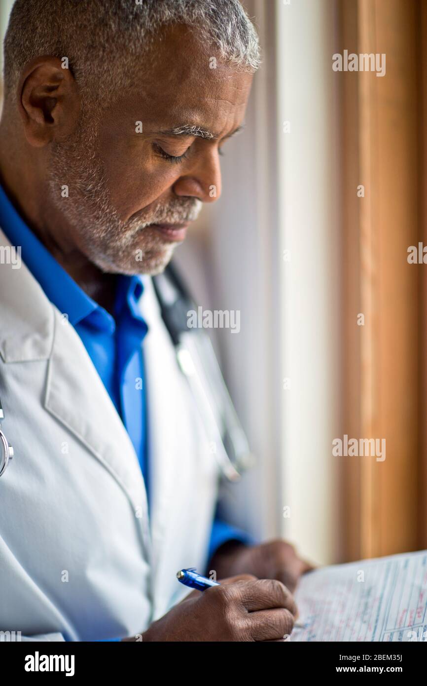 Reife männliche Arzt Schreiben Notizen Stockfoto