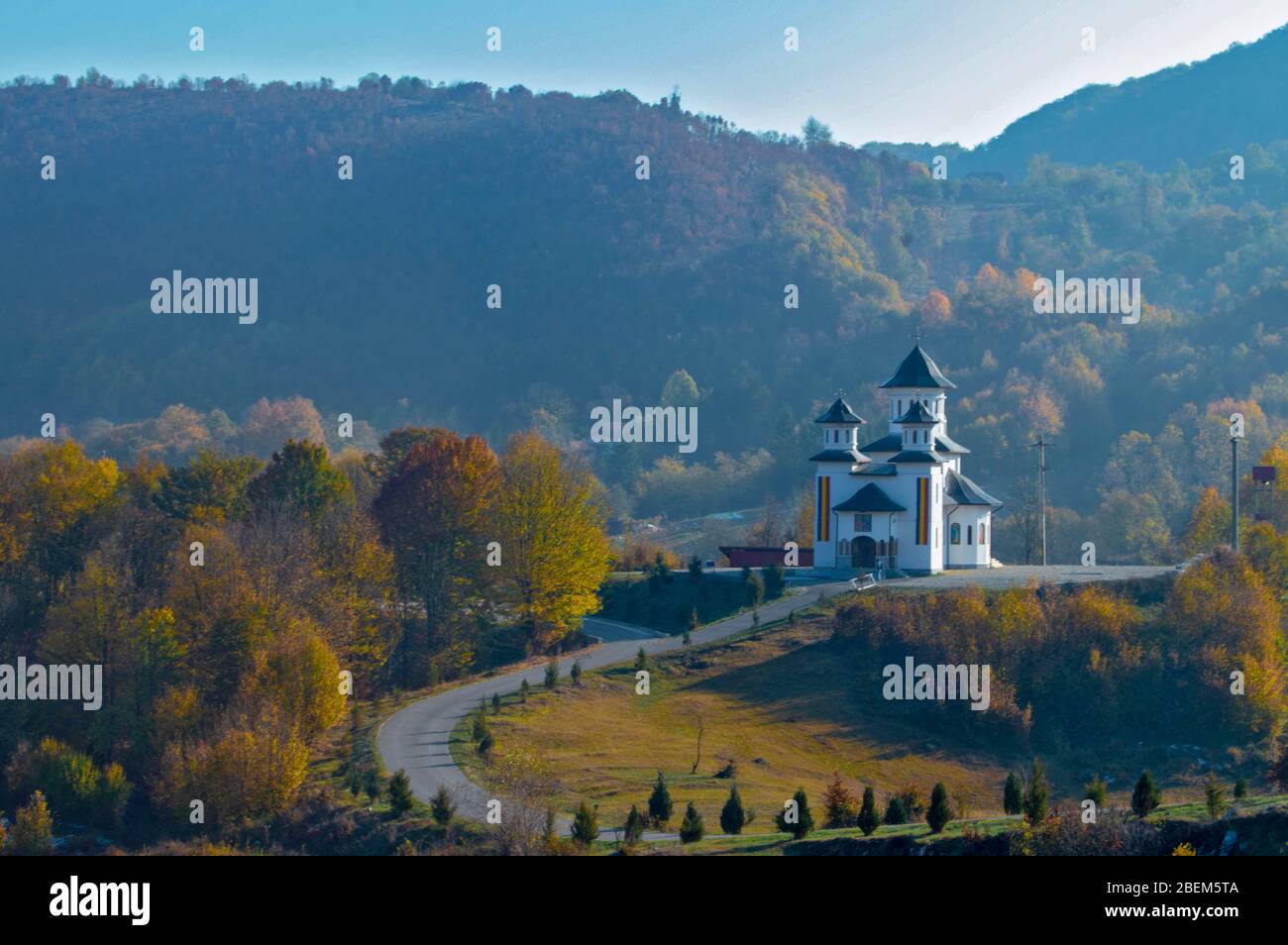 Märchenhafte Landschaft: Landstraße, die zur majestätischen Kirche auf einem Hügel mitten in der Natur führt, Herbst/Herbst Farben und blauer Himmel umgeben die Ponoare Stockfoto