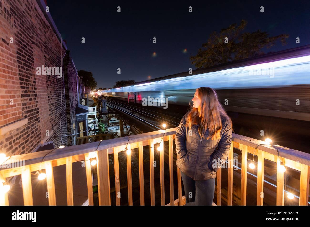 Frau auf ihrem Holzdeck im Lincoln Park, als ein erhöhter Zug vorbei fährt. Stockfoto