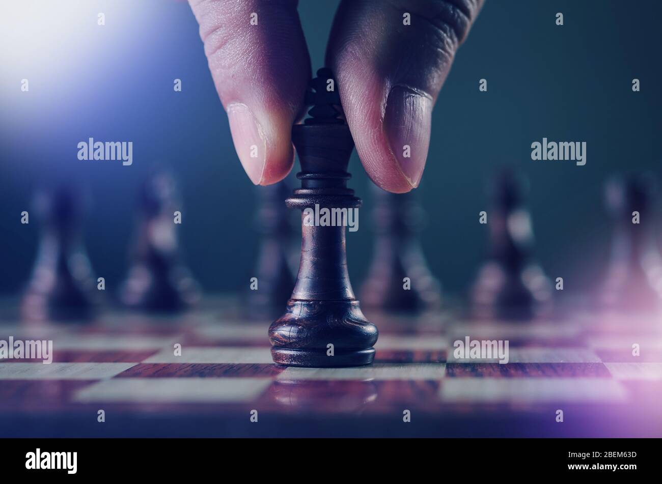 Strategie und Planung Konzept, Nahaufnahme der menschlichen Hand beim Halten oder Bewegen König Schachfigur in kühlen Farbton und Licht Leck-Effekt Stockfoto