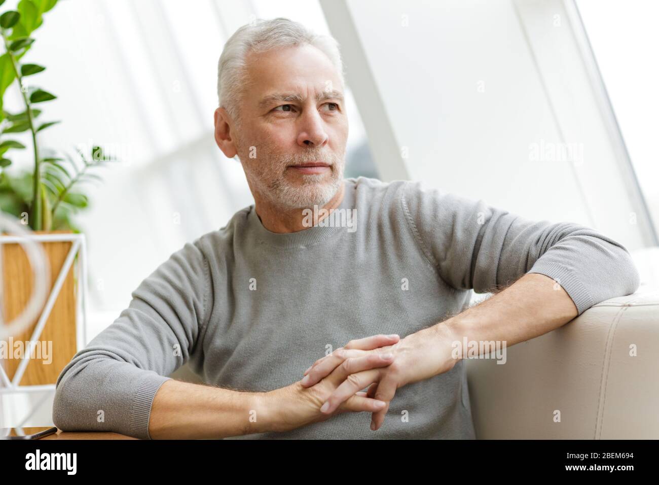 Bild eines älteren grauhaarigen bärtigen Geschäftsmannes sitzen im Café. Stockfoto