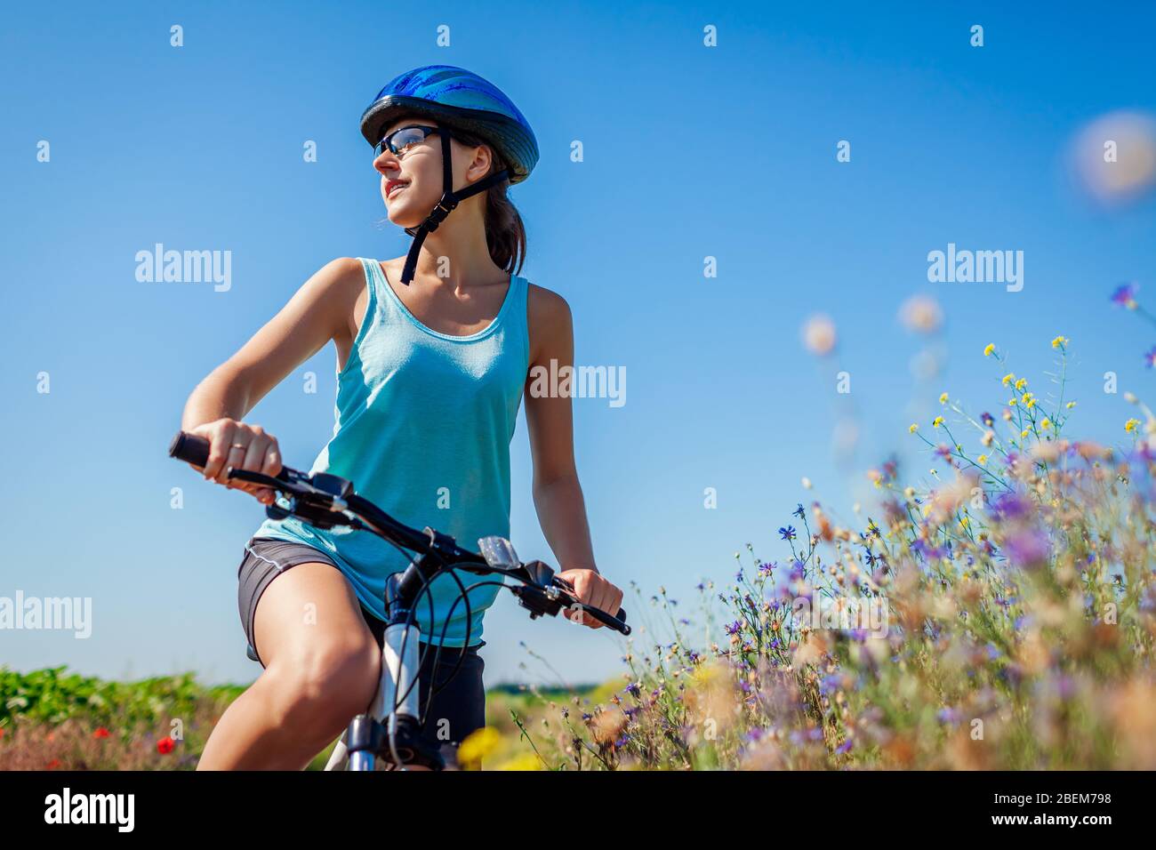 Glückliche junge Frau Radfahrer trägt Helm mit Ruhe nach Fahrrad im Sommerfeld genießen Landschaft. Stockfoto