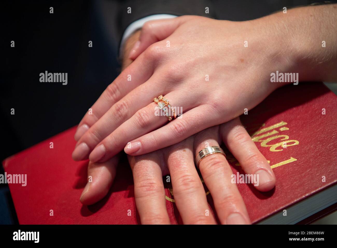 Braut und Bräutigam geben eine bibel mit Eheringen an. Stockfoto