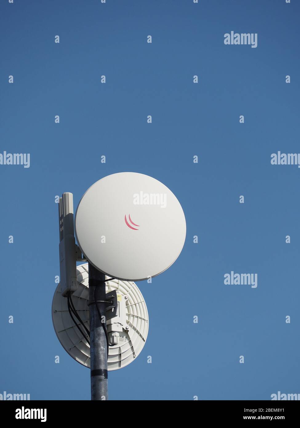 Antennen/Router des ländlichen Breitband-Wireless-Internetdienstes. Schalen für Backhaul zu Masten auf dem Netzwerk-Backbone, aufrechte Antennen für lokale Räumlichkeiten. Stockfoto