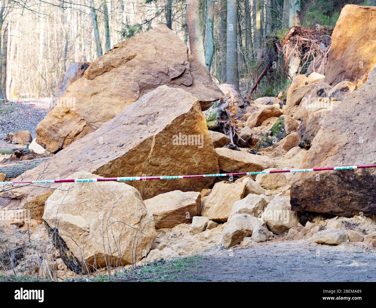 Bereich mit Polizeiband markiert, nicht Eintritt. Eingestürzte Felsbrocken faal unten von Hang und blockierten Waldweg. Gefahrenstelle Stockfoto