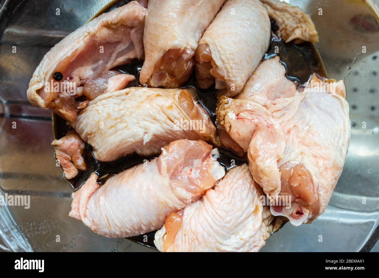 Rohes Hähnchenschenkel, marinieren in einer Glasschüssel vor dem Kochen. Stockfoto