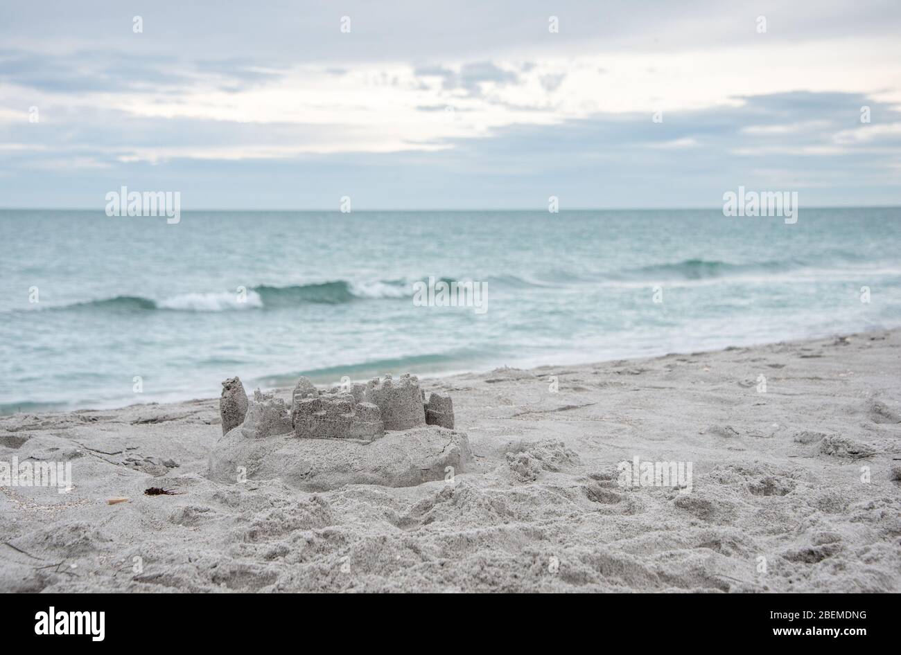 Ein Sandschloss am Strand mit sanften Wellen, eine ruhige Szene für einen Florida Familienurlaub / Urlaub in der Natur. Stockfoto