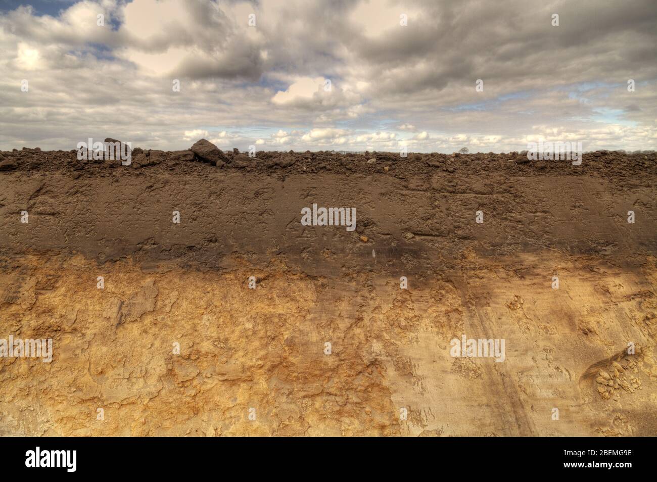 Die Seite eines frisch gegrabenen Feldrainage Graben zeigt Bodenschichtung humos Oberboden und Eisenniederschläge im Untergrund Stockfoto