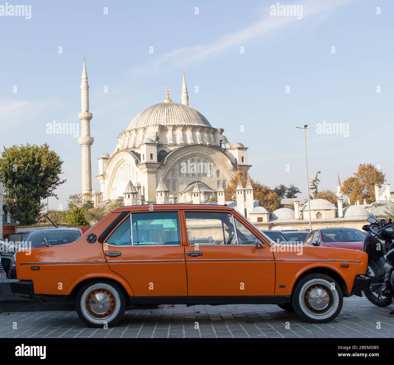 Altes klassisches orangenes Fahrzeug im Parkhaus fotografiert. Im Hintergrund befindet sich eine Moschee. Nahaufnahme. Stockfoto