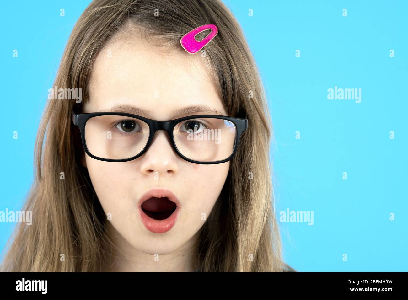 Porträt von überraschten Kind Mädchen tragen aussehende Brille isoliert auf blauem Hintergrund. Stockfoto