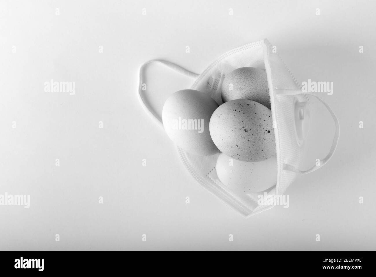 Osterkonzept. Eier in Schutzmaske. Coronavirus, Quarantäne, Schwarz-Weiß-Foto Stockfoto