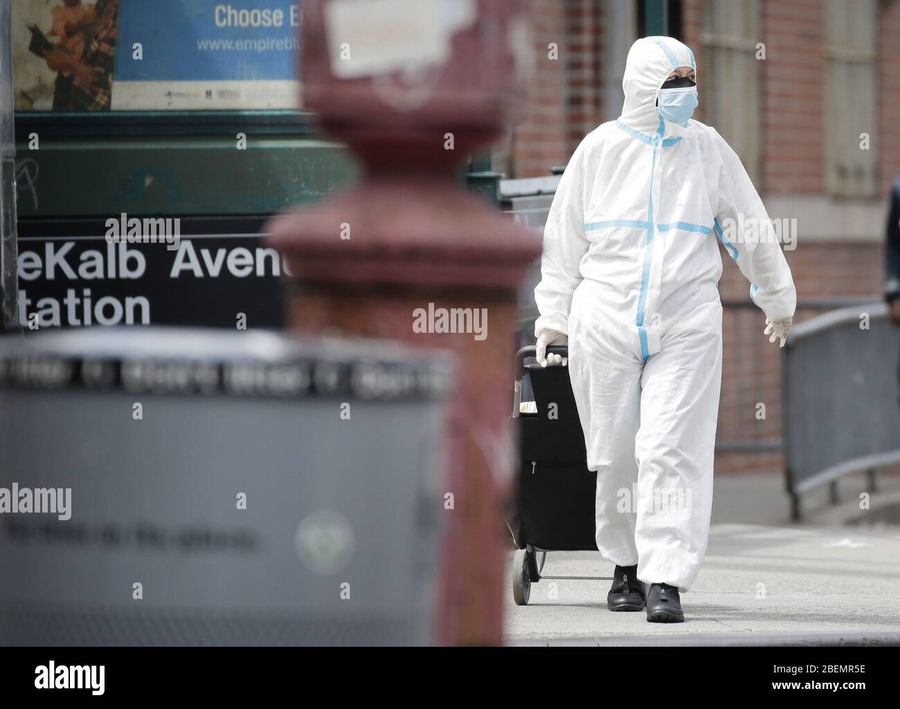 Brooklyn, Usa. April 2020. Ein Fußgänger, der Kopf bis Fuß in Schutzkleidung überdeckt, kreuzt am Dienstag, den 14. April 2020, auf dem Bürgersteig in der Nähe des Wyckoff Heights Medical Center in New York City. Bis heute sind fast 285,000 Menschen mit dem Coronavirus infiziert und mehr als 14,000 Menschen sind in NY, NJ und CT gestorben. Es gibt jedoch Anzeichen dafür, dass die Kurve abflacht. Foto von John Angelillo/UPI Quelle: UPI/Alamy Live News Stockfoto