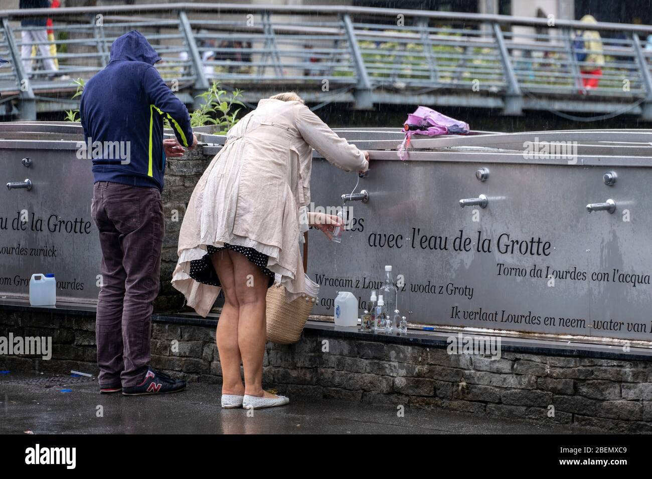Pilger sammeln Weihwasser aus Wasserhähnen in der Wallfahrtskirche in Lourdes, Frankreich, Europa Stockfoto