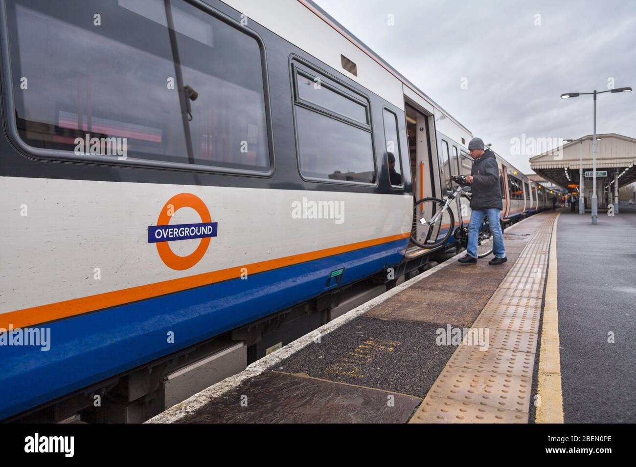 Passagier, der mit einem Fahrrad/Fahrrad am Bahnhof Clapham Junction mit dem Overground-Logo in einen TFL London Overground-Zug der Klasse 378 einsteigen wird Stockfoto