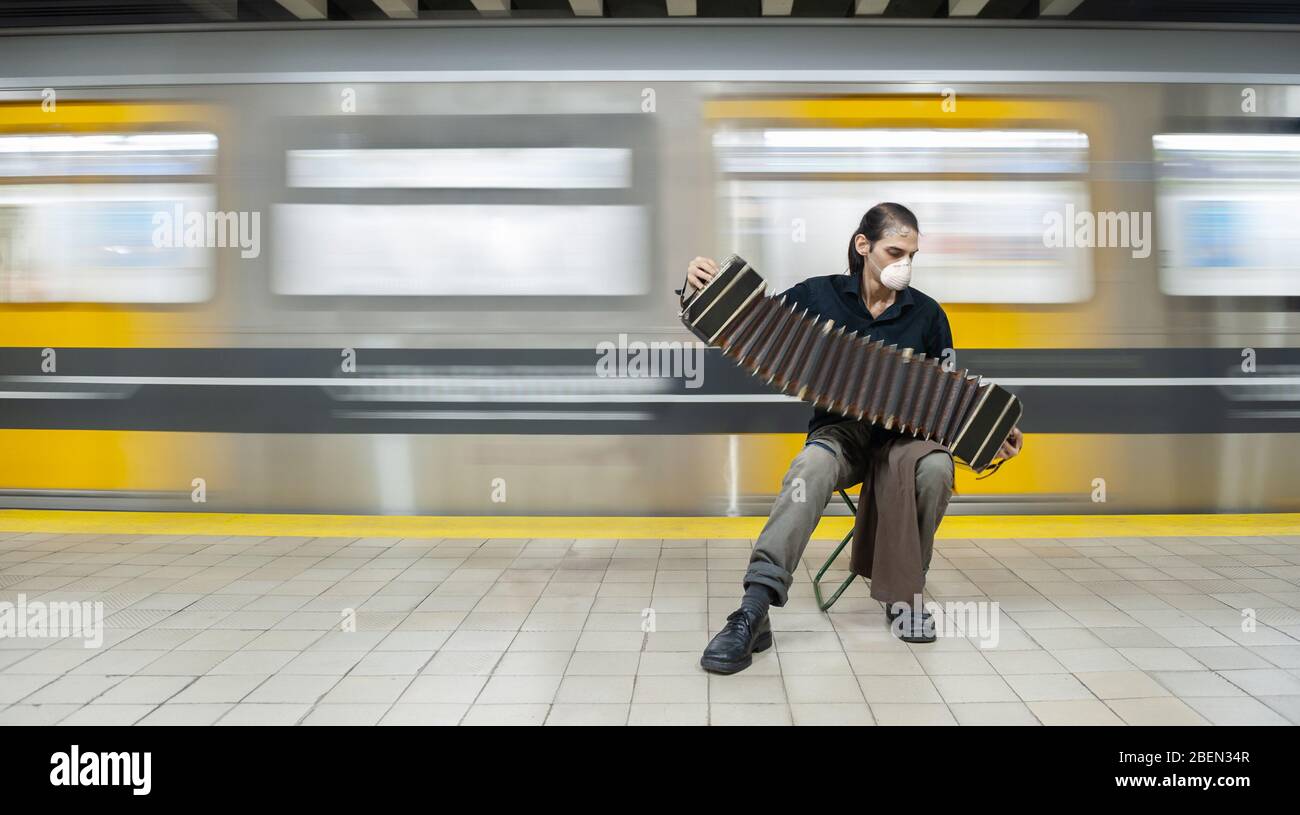 Bandoneon mit medizinischer Gesichtsmaske spielen, mit der U-Bahn in Bewegung. Stockfoto