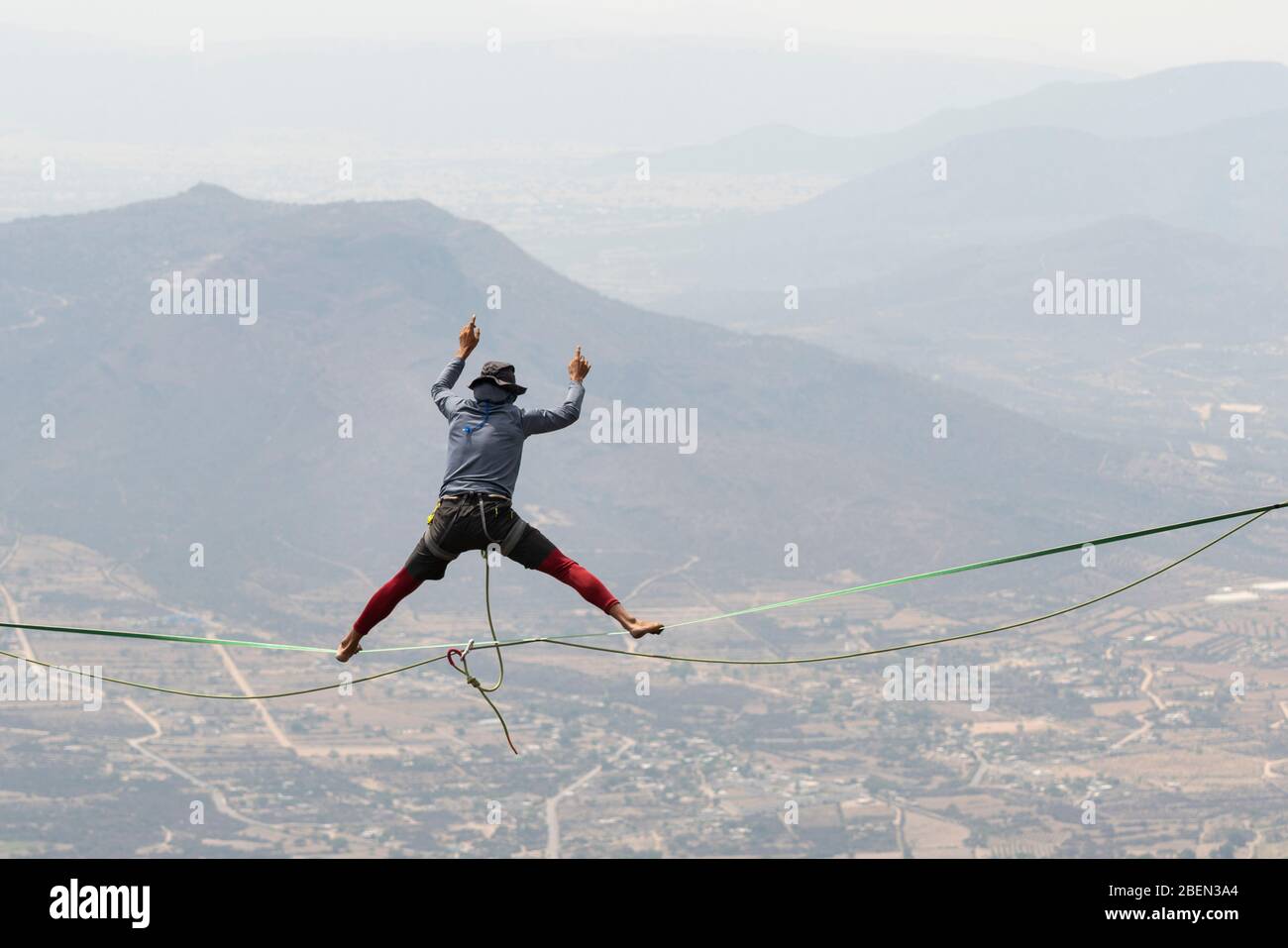 Ein Mann balanciert mit offenen Beinen in einer Highline bei Los Frailes Stockfoto