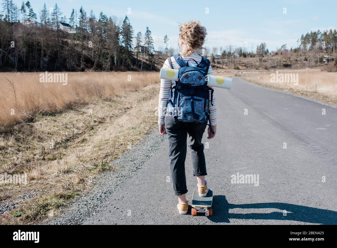 Frau, die beim Skateboard-Skaten eine Yogamatte in einem Rucksack trägt Stockfoto
