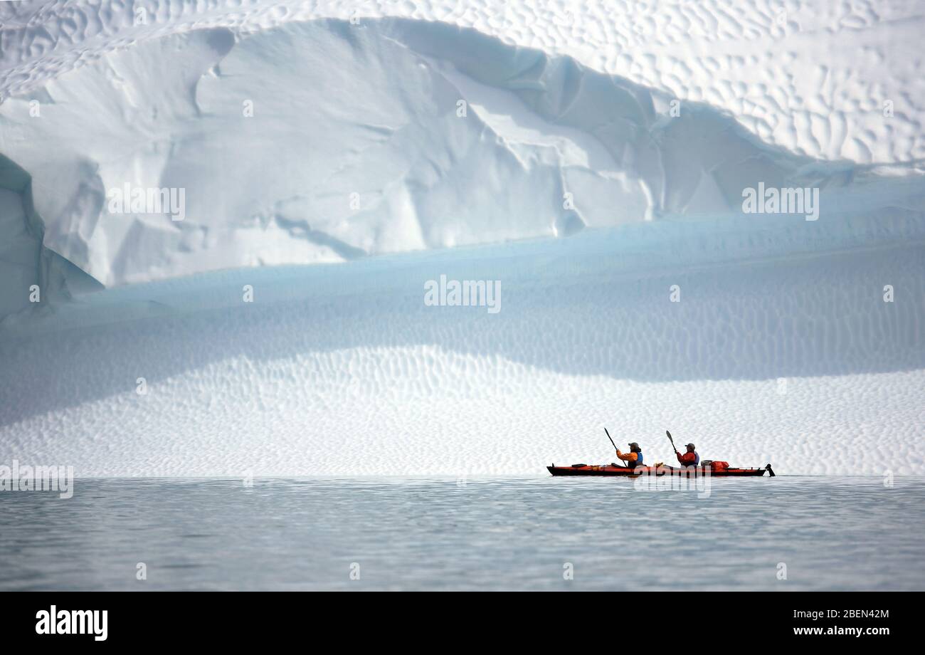 Zwei Männer rudern ihr Seekajak auf einem Eisberg in Grönland Stockfoto