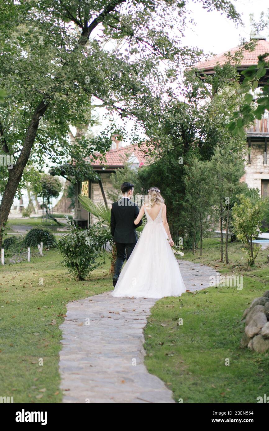 Die Braut und der Bräutigam posieren auf der Hand. Wenn die Sonne untergeht, am Veranstaltungsort der Hochzeit. / Hochzeitstag und Paarshooting / die Braut hält eine Brautflowe Stockfoto