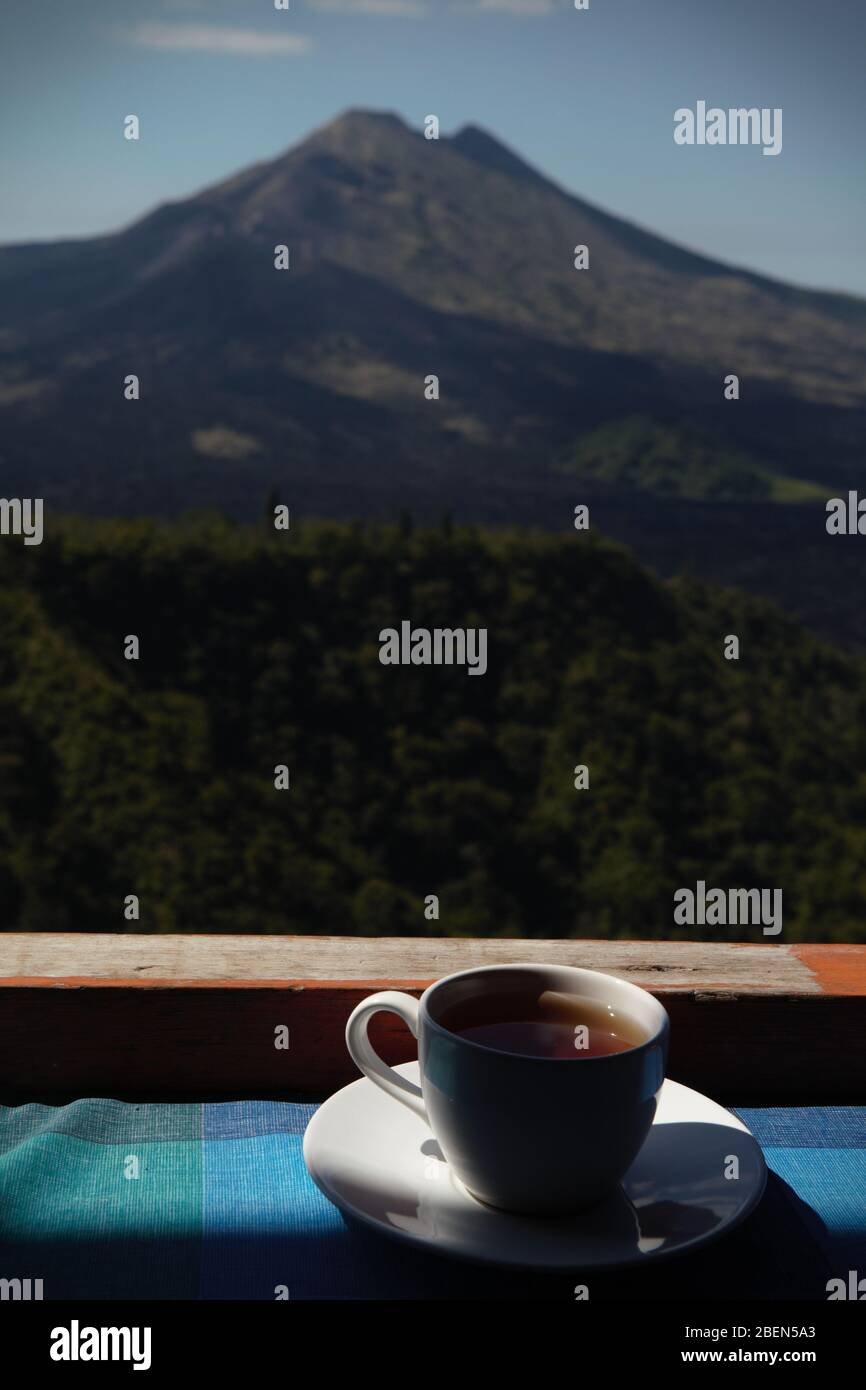 Eine Tasse Tee auf dem Tisch des Restaurants, mit dem Vulkan Mount Batur im Hintergrund. Bali, Indonesien. Stockfoto