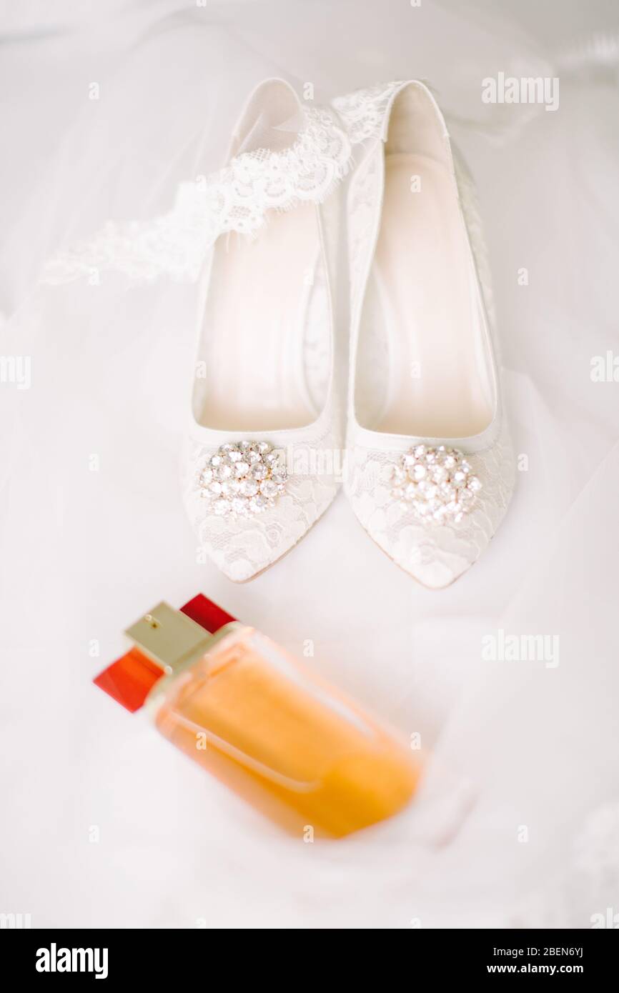 Brautschuhe auf Tüll. Edelstein und Spitze. Parfümflasche. Stockfoto