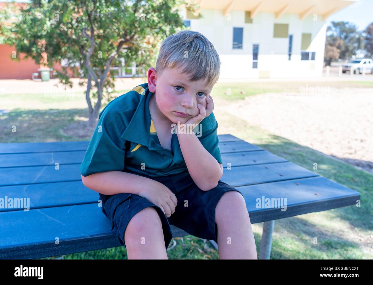 Covid-19 Ausbruchsschulen geschlossen. Traurig Schuljunge gelangweilt Gefühl depressiv und einsam in leerem Spielplatz als Schule geschlossen ist. Einschränkungen und Sperrungen Stockfoto