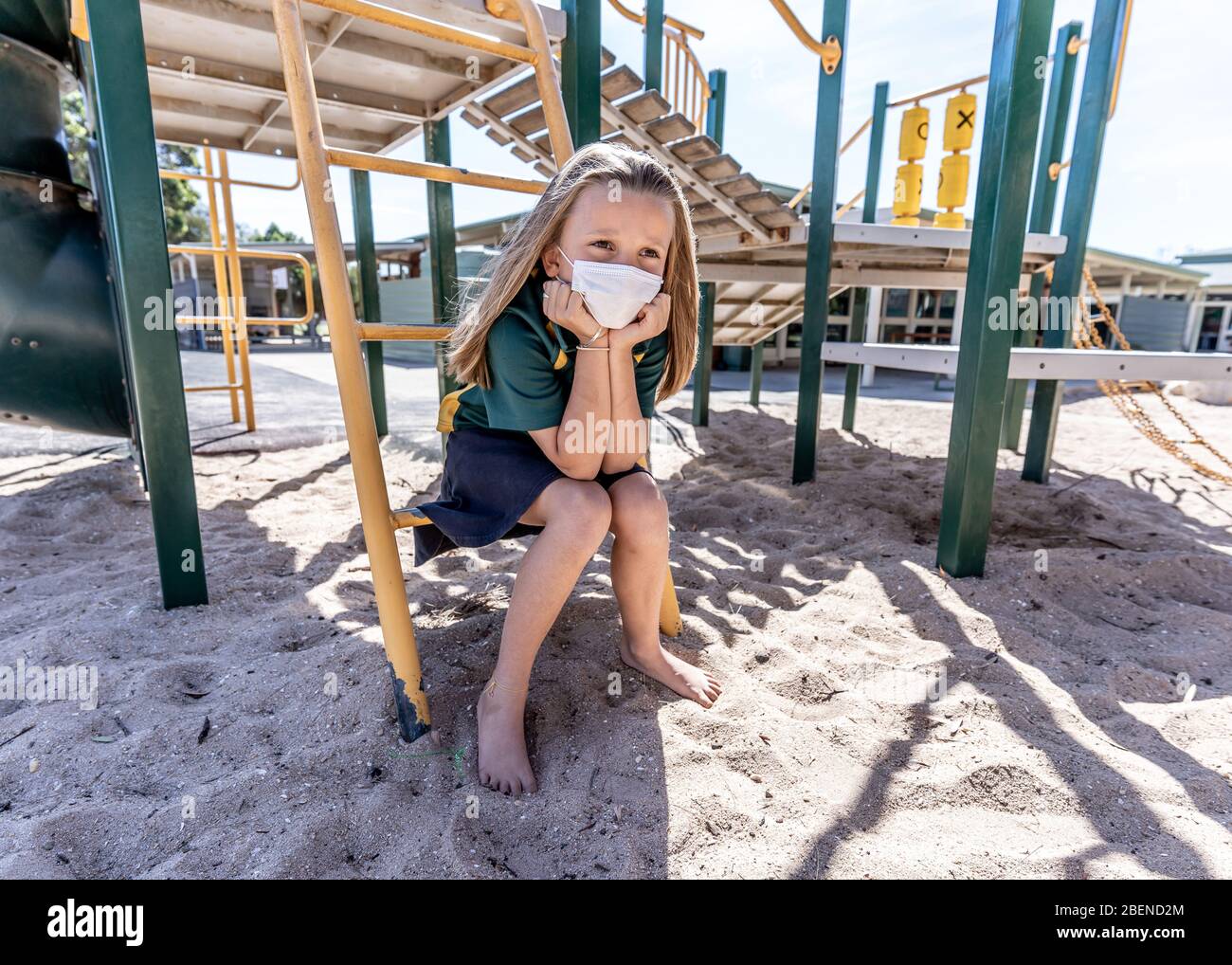 Covid-19 Ausbruchschulen geschlossen. Trauriges Schulmädchen mit Gesichtsmaske gelangweilt sich depressiv und einsam auf leerem Spielplatz, als die Schule geschlossen ist. Einschränken Stockfoto