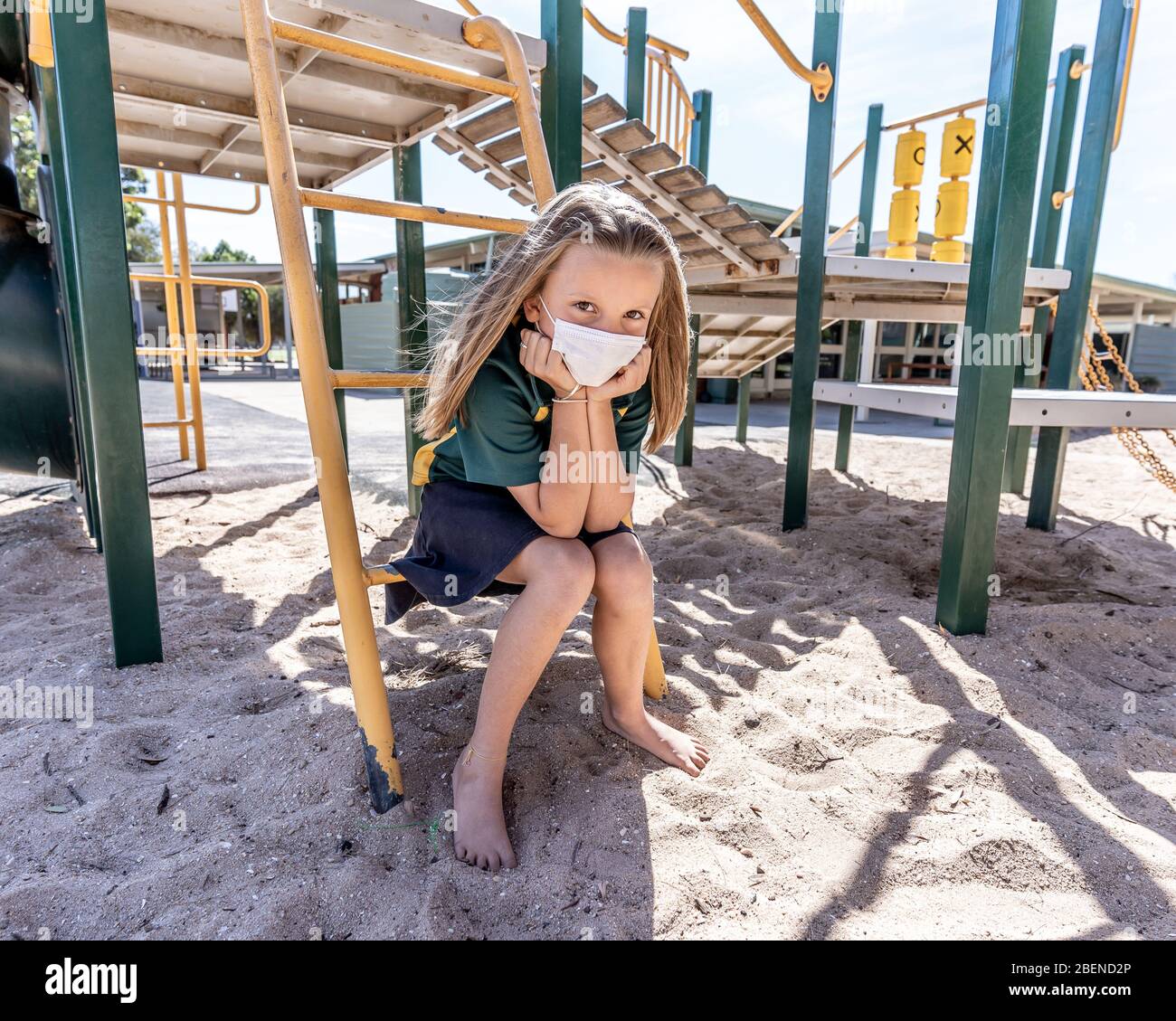 Covid-19 Ausbruchschulen geschlossen. Trauriges Schulmädchen mit Gesichtsmaske gelangweilt sich depressiv und einsam auf leerem Spielplatz, als die Schule geschlossen ist. Einschränken Stockfoto