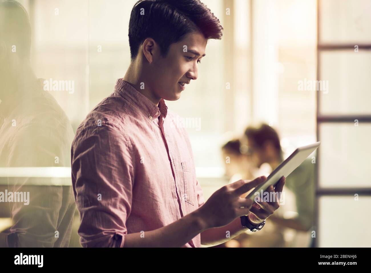 Erfolgreiche junge asiatische Unternehmer auf der Suche nach Tablet-Computer im Büro Stockfoto