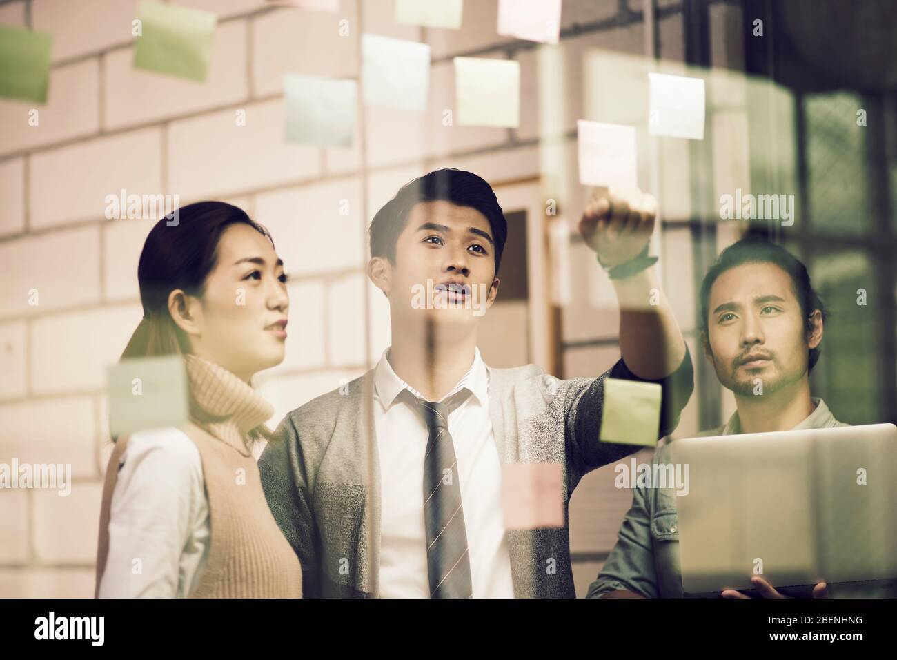 Drei asiatische Kleinunternehmer junge Unternehmer, die mit Haftnotizen im Büro diskutieren Stockfoto