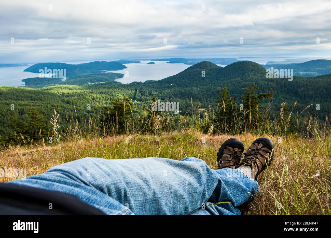 Eine erste Person Blick auf einen Mann auf einem Hügel entspannen und genießen einen spektakulären Blick auf die San Juan Inseln. Stockfoto