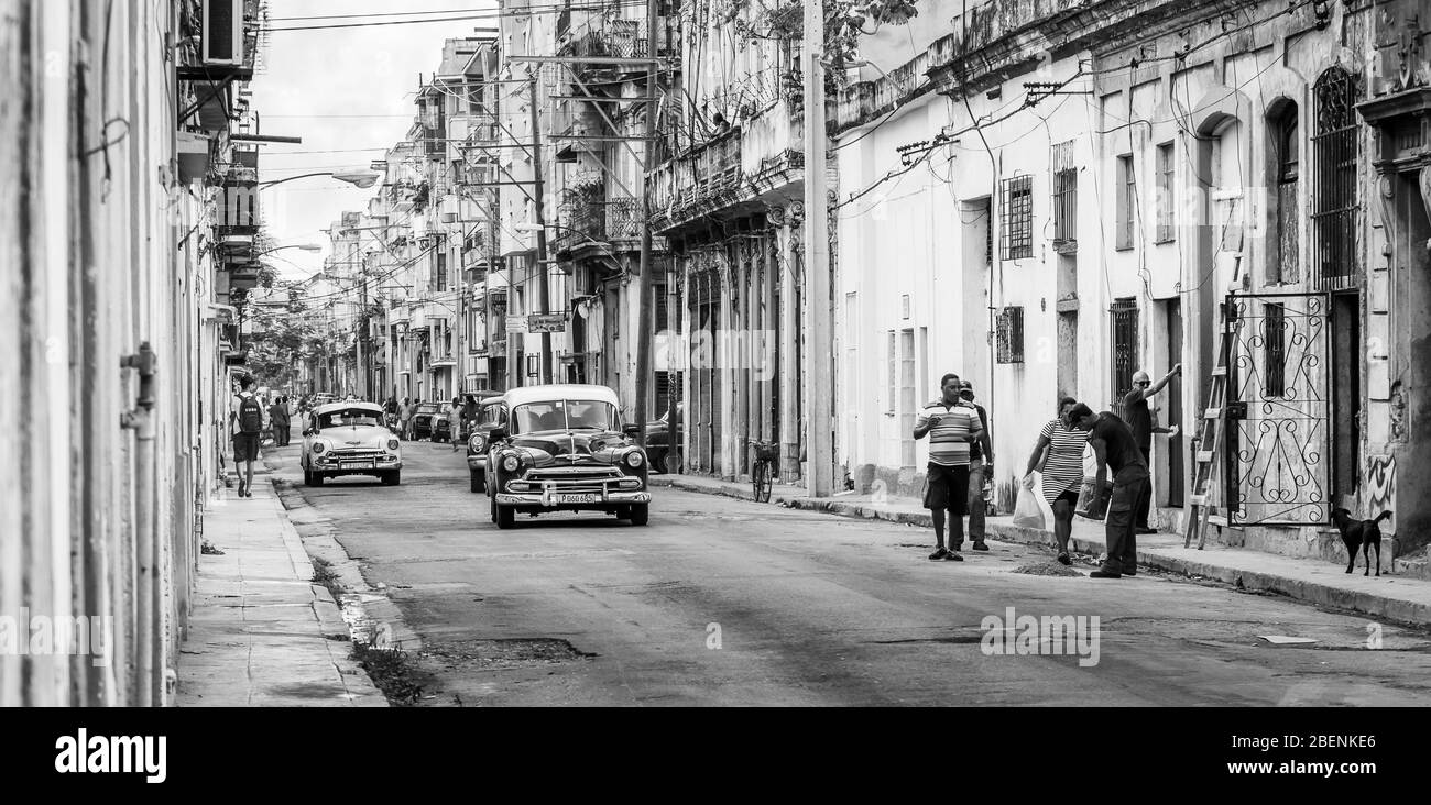 Bunte Gebäude, bunte Autos und Einheimische besetzen eine Straße in Havanna, Kuba im November 2015. Stockfoto