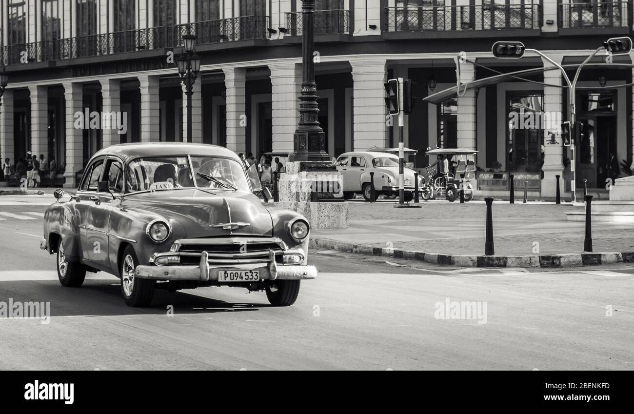 Ein grünes klassisches Auto aus den 50er Jahren fährt den Prado im Herzen von Havanna (Kuba) hinunter, so wie die warme Sonne in der Ferne während der Zeit untergeht Stockfoto