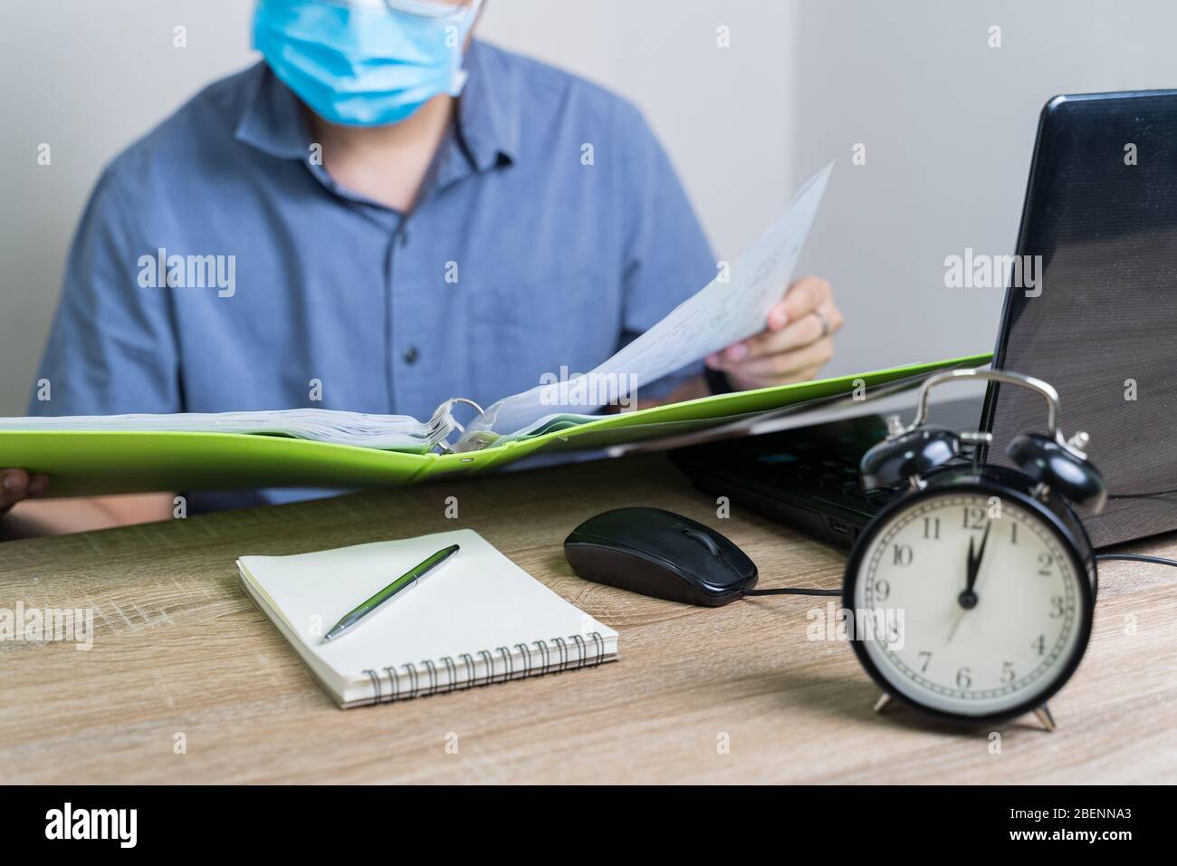 Arbeit von zu Hause aus während des Ausbruchs des Virus. Um Mitternacht arbeitete Geschäftsmann von zu Hause aus, er trug eine Gesundheitsmaske und beobachtete Berichte Stockfoto