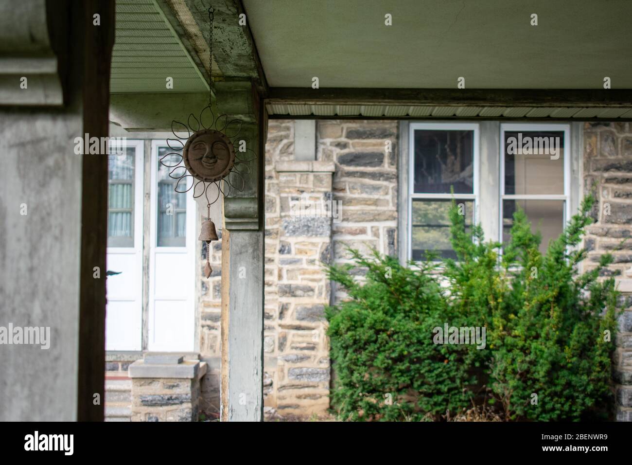 Ein Hängelchen lächelnder Sonnenschmuck unter einer überdachten Terrasse in einem Kopfsteinpflaster Gebäude Stockfoto