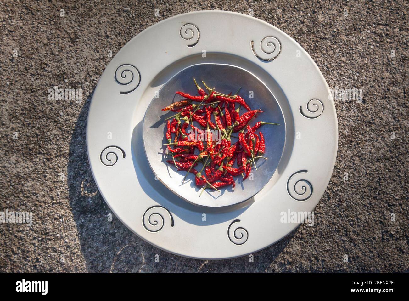 Außenfoto von roten Paprika auf zwei Metallplatten auf Kieselstein strukturierten Hintergrund Stockfoto