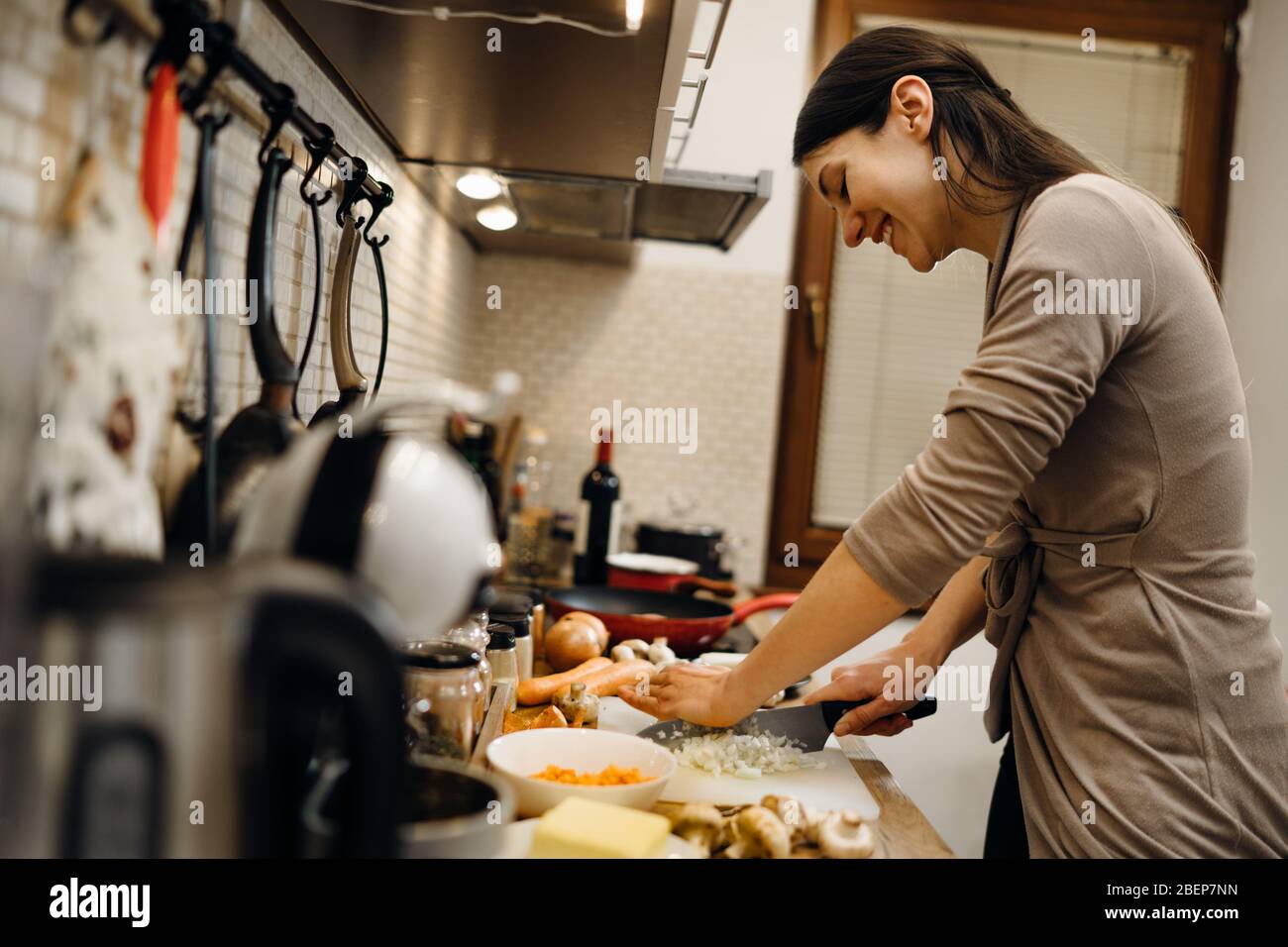 Junge Hausfrau Anfänger kochen Schneiden Zwiebel.Schneiden Zwiebeln auf einem Schneidebrett.Schneiden, würfeln und zerhacken Zwiebel.Vorbereitung zum Kochen. Gesunde Ernährung und li Stockfoto