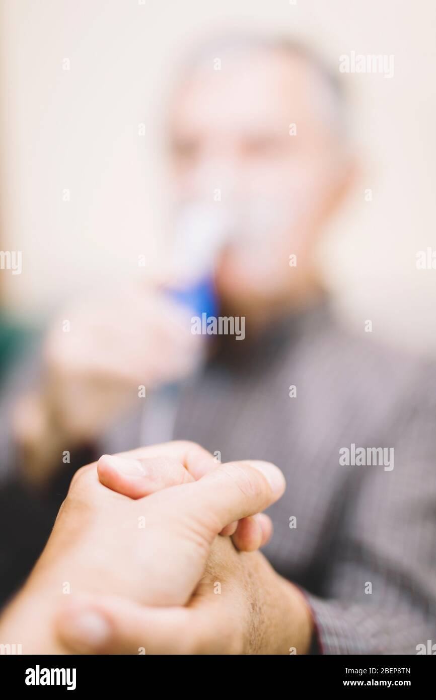 Leitender Mann, der medizinische Geräte für die Inhalation mit Atemschutzmaske verwendet, Vernebler im Zimmer Stockfoto