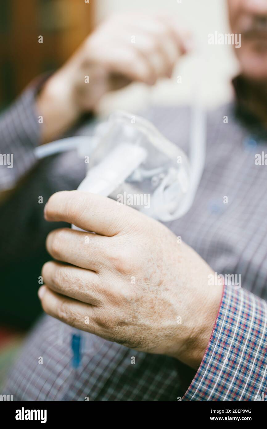 Leitender Mann, der medizinische Geräte für die Inhalation mit Atemschutzmaske verwendet, Vernebler im Zimmer Stockfoto