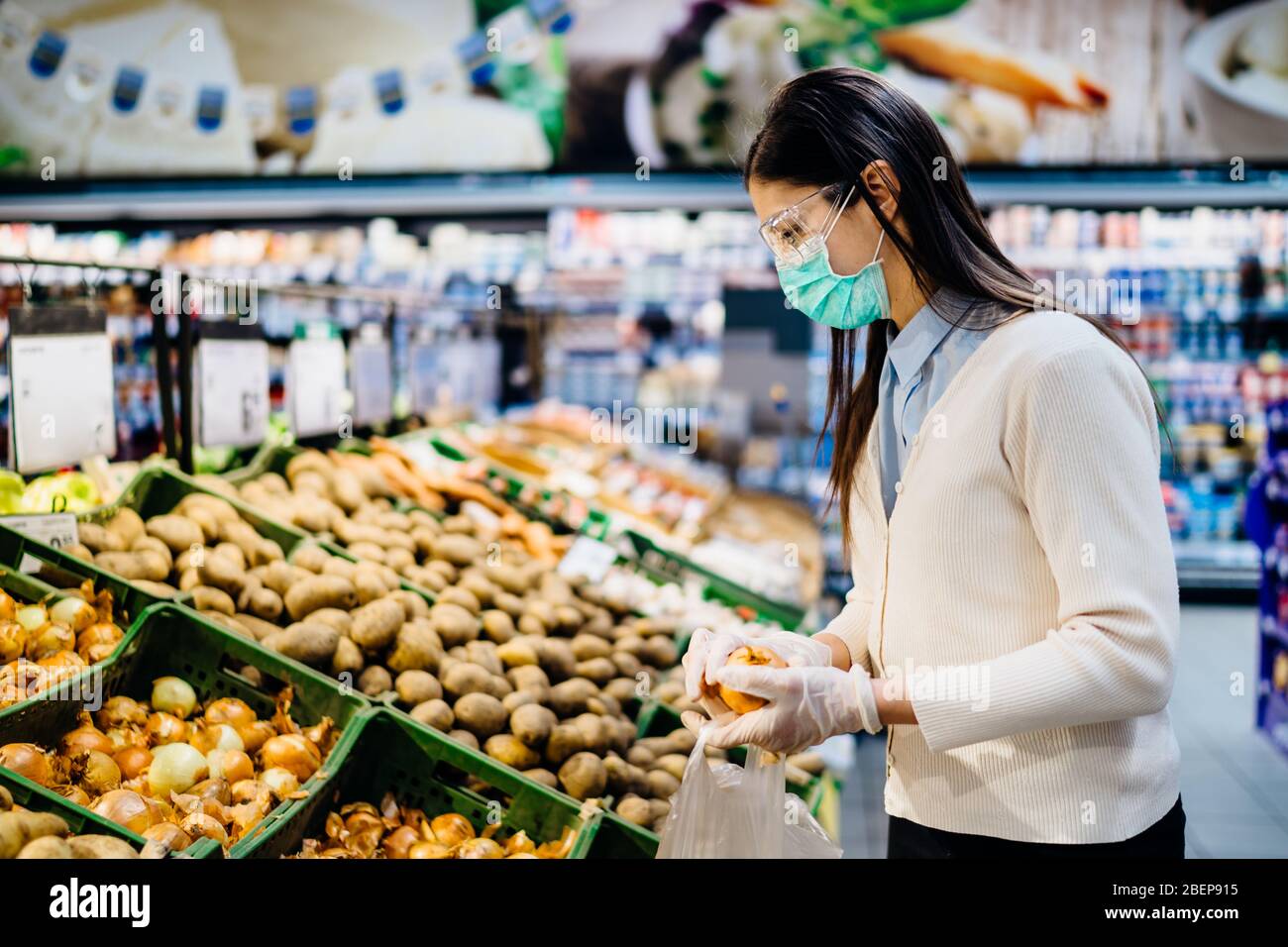 Frau mit hygienischen Maske Kauf im Supermarkt Lebensmittelgeschäft für frische Grüns, Budget-Shopping für Lieferungen während der Pandemie.Kauf von Bio vegetabl Stockfoto