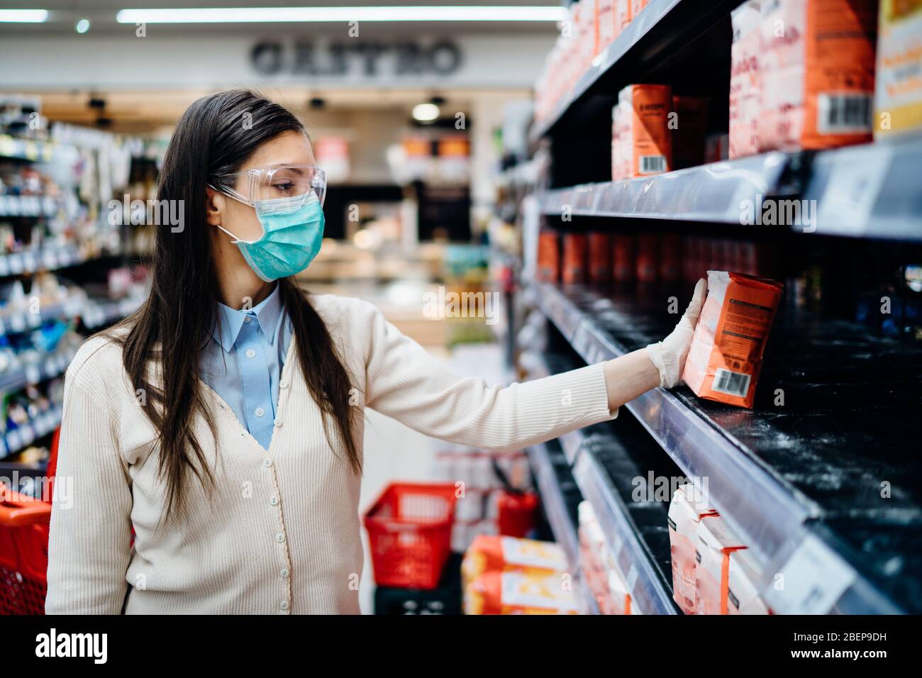 Frau trägt Maske Kauf Lebensmittel / Vorräte im Supermarkt mit ausverkauften Produkten.Lebensmittel liefert Mehl Mangel.leere Regale aufgrund neuartiger Coronavirus Stockfoto