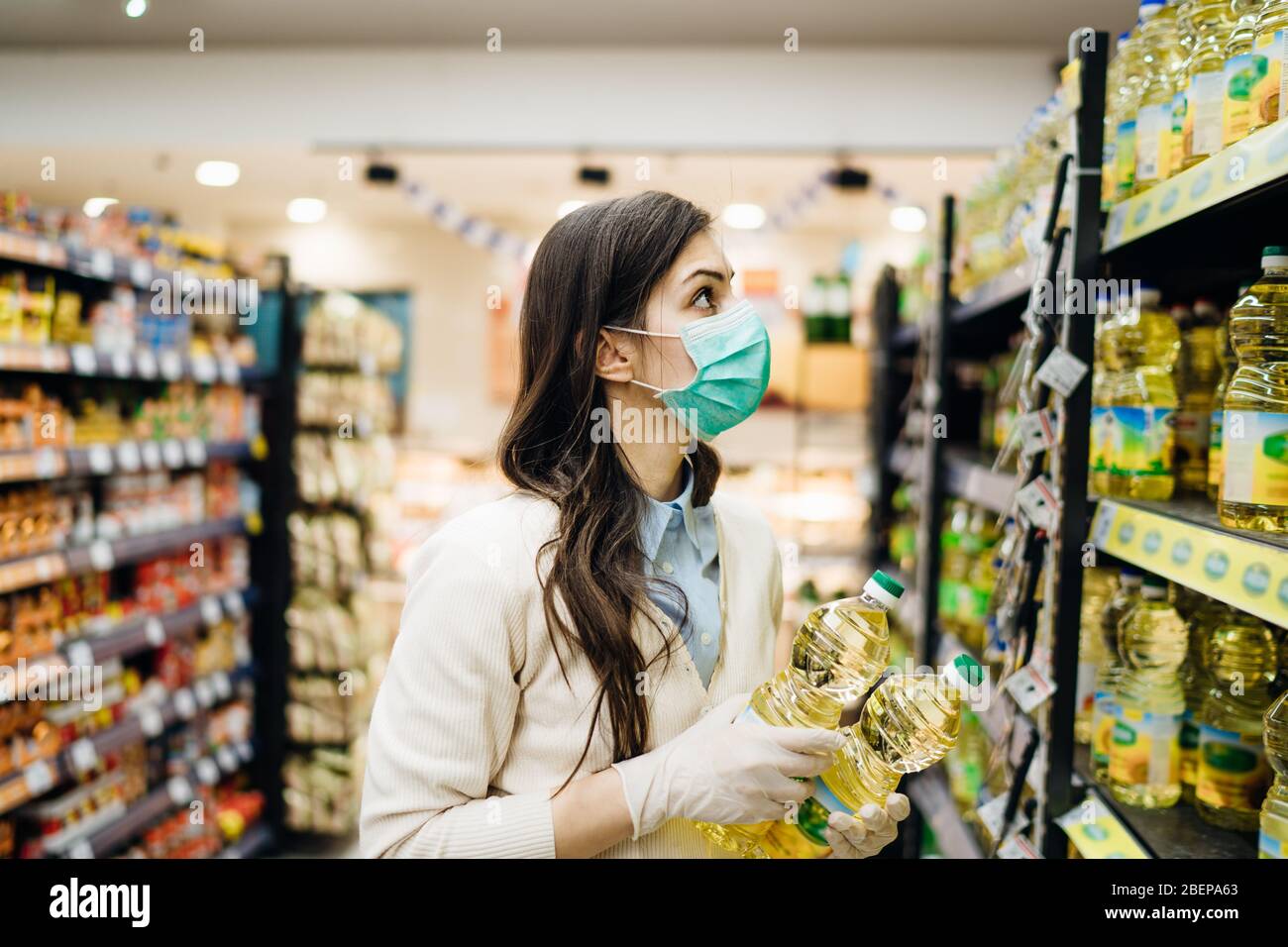 Frau mit Maske sicher einkaufen für Lebensmittel inmitten der Coronavirus-Pandemie in sortierten Lebensmittelgeschäft.COVID-19 Lebensmittel im Supermarkt kaufen.Panik kaufen, Stockfoto