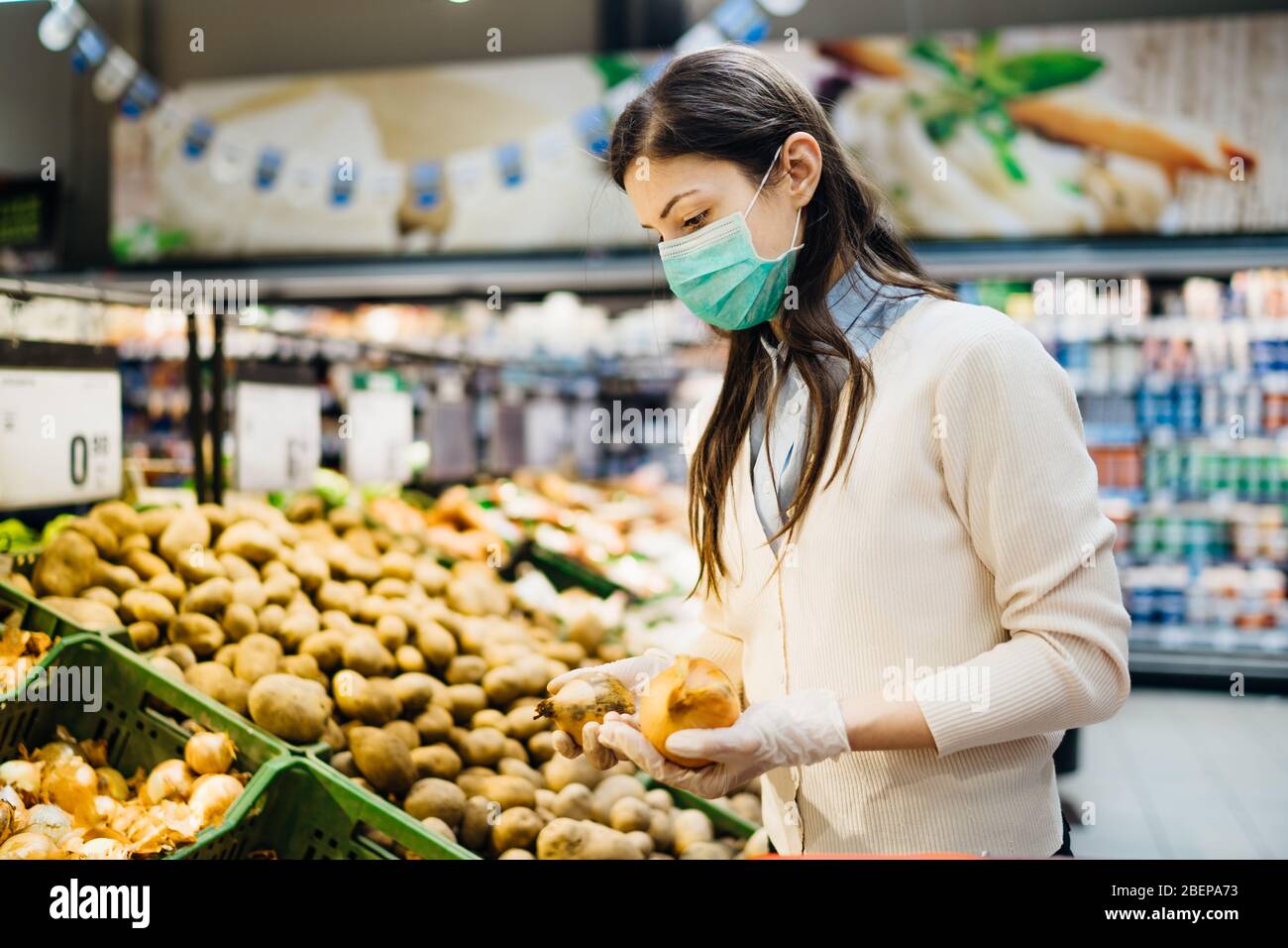 Frau mit Maske sicher einkaufen für Lebensmittel inmitten der Coronavirus-Pandemie in einem sortierten Lebensmittelgeschäft.COVID-19 Lebensmittel im Supermarkt kaufen.Panik kaufen Stockfoto